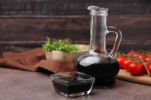 Aged balsamic vinegar with tomatoes and bowl of lettuce