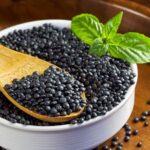 Black beluga lentils in a round white bowl with spoon