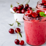 Cherry smoothies with cherries next to glasses of smoothies