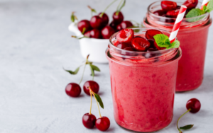 Cherry smoothies with cherries next to glasses of smoothies