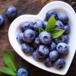 Costco blueberries in heart shaped dish with blueberries and green leaf
