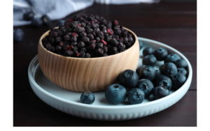 Freeze dried blueberries in a bowl next to fresh blueberries