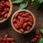 What do goji berries taste like? with two wooden bowls of berries by leaves